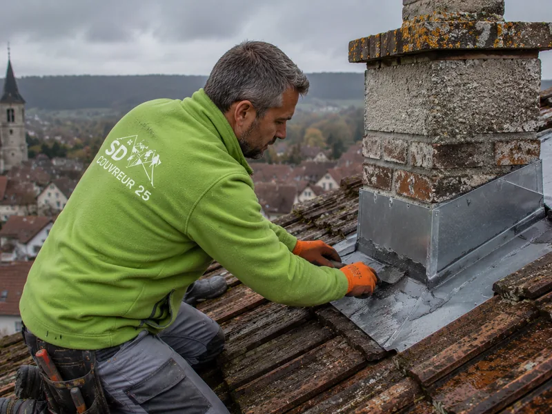 Artisan posant une bâche de protection sur une toiture qui fuit à Besançon